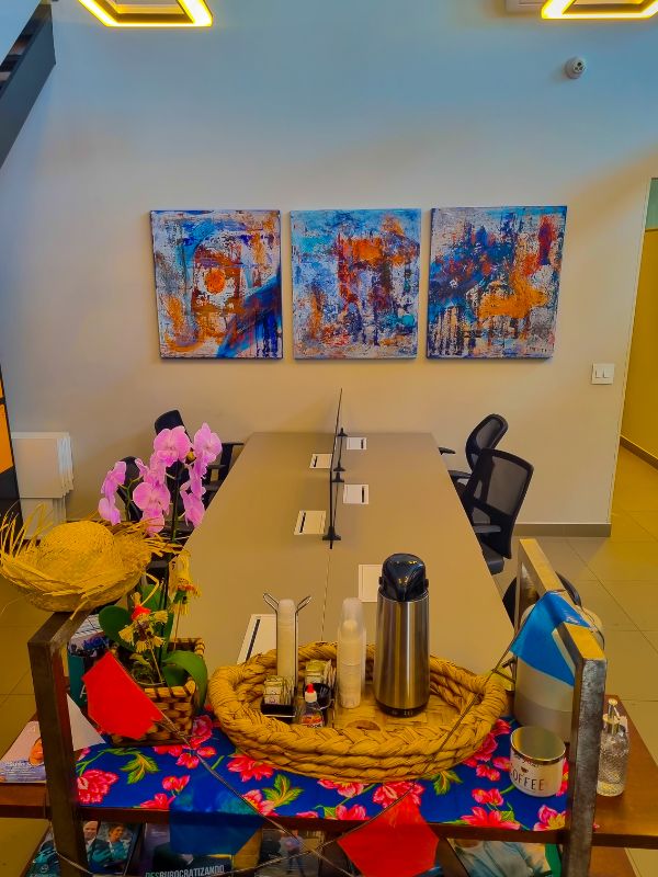 Imagem da mesa compartilhada localizada no salão do CW15, com um carrinho em primeiro plano com itens decorativos de festa junina.