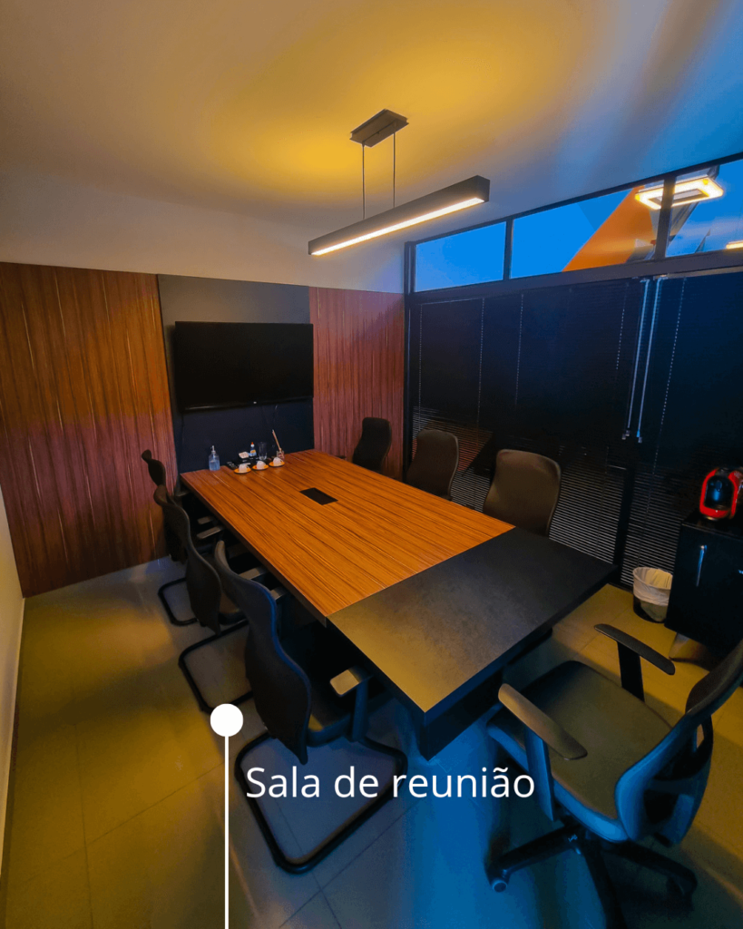 Imagem da Sala de Reuniões mostrando toda a estrutura: Mesa, cadeiras, televisão e máquina de Café